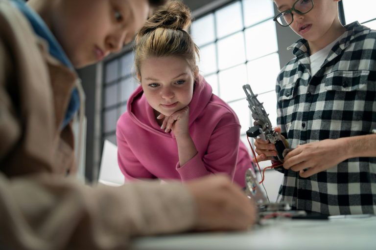 Group of kids working together on project with electric toys and robots at robotics classroom, close